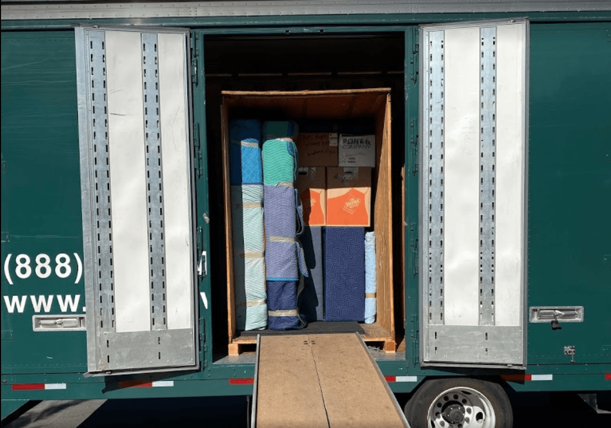 Open moving truck with boxes and furniture wrapped in blankets.