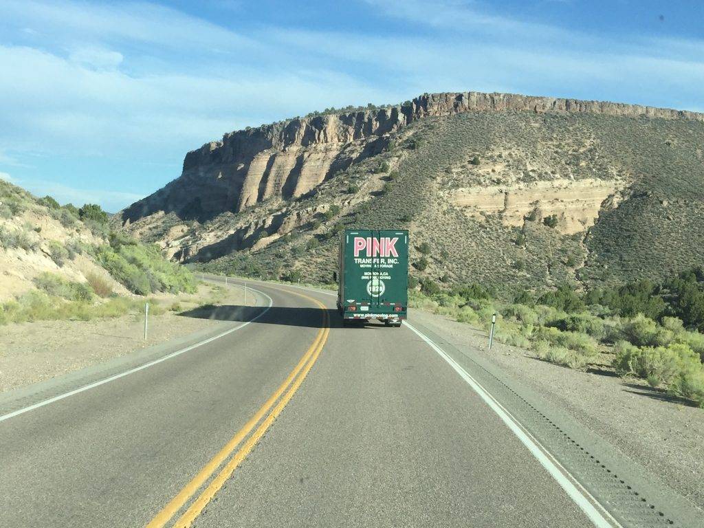pink moving truck driving in the mountains